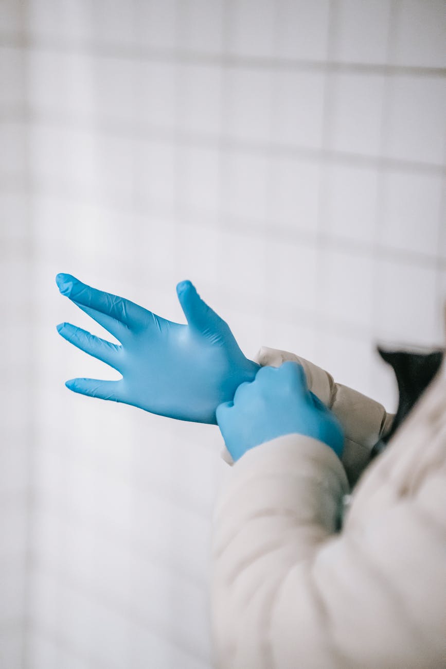 crop faceless person in outerwear putting on latex gloves